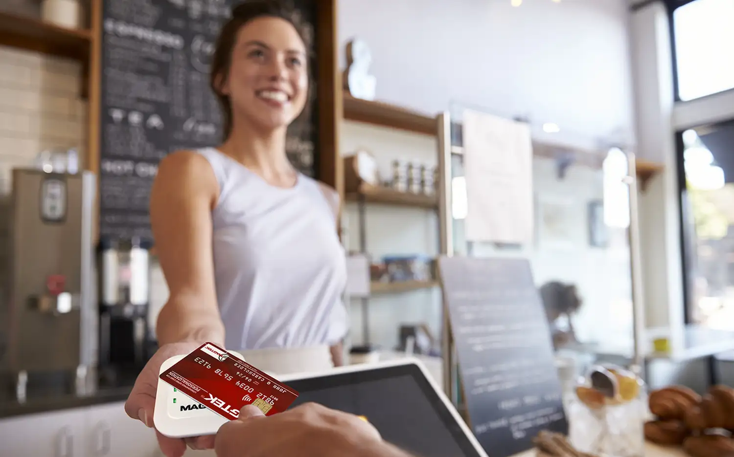 An image of a person using their tap-to-pay capable bank card to effortlessly tap a MagTek device at a cafe for seamless payments.