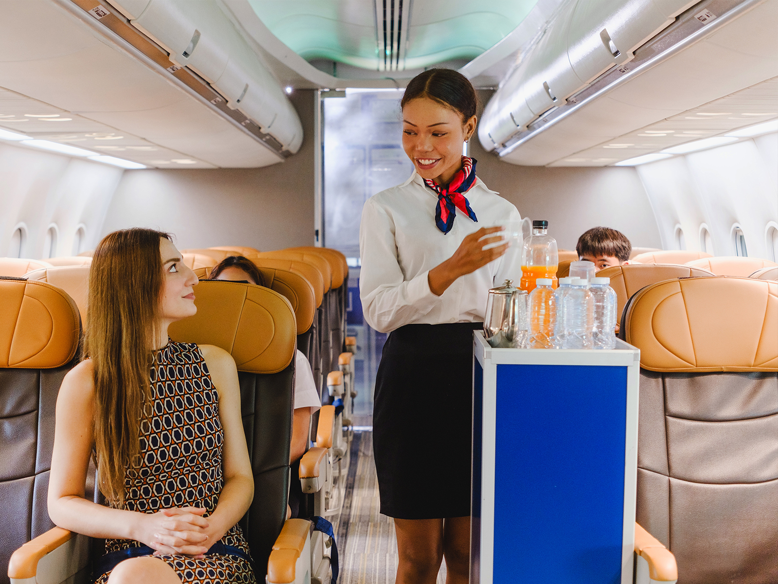 Flight attendants serving passengers in an airplane cabin aisle