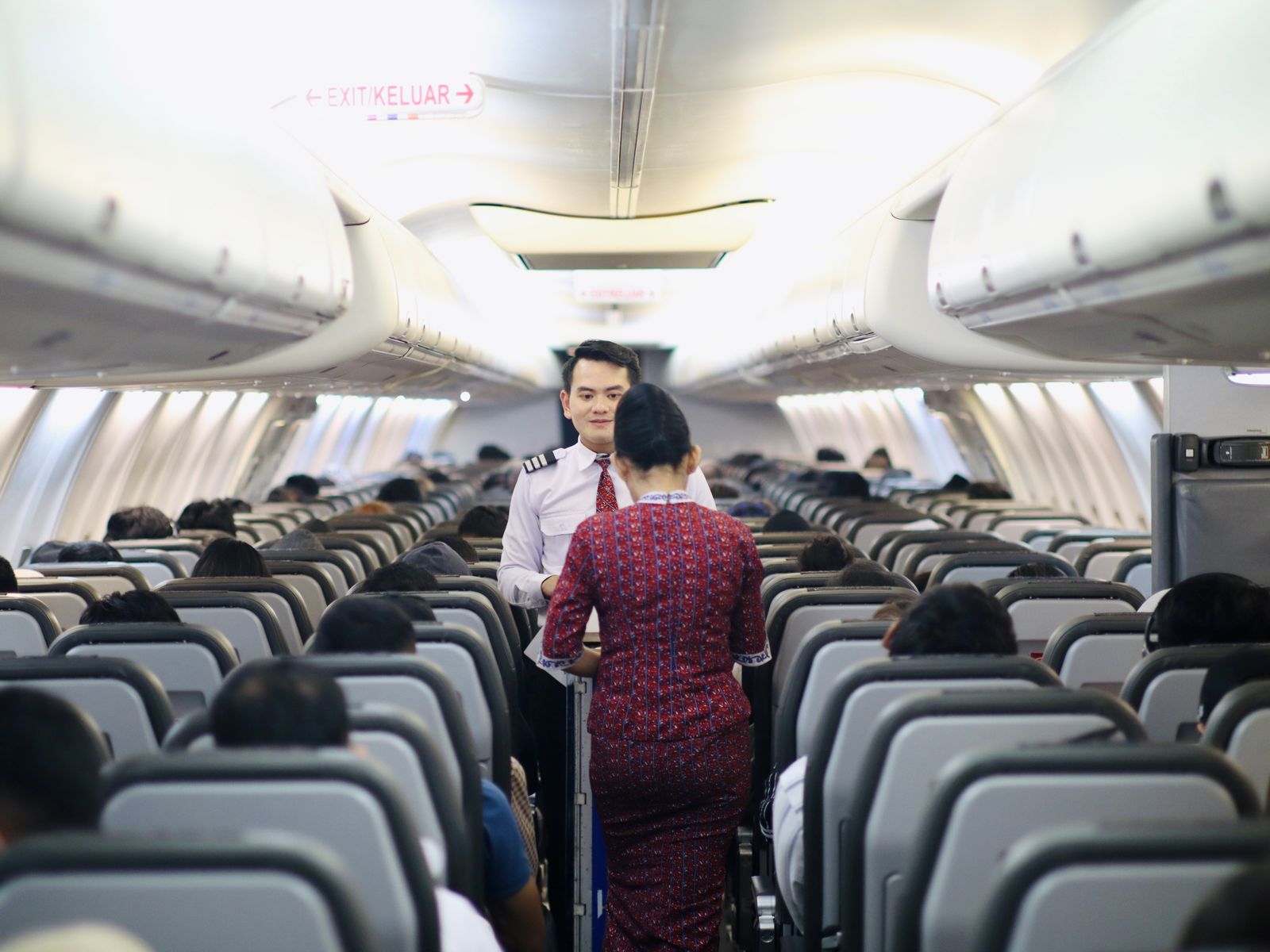 Flight attendants serving passengers in an airplane cabin aisle