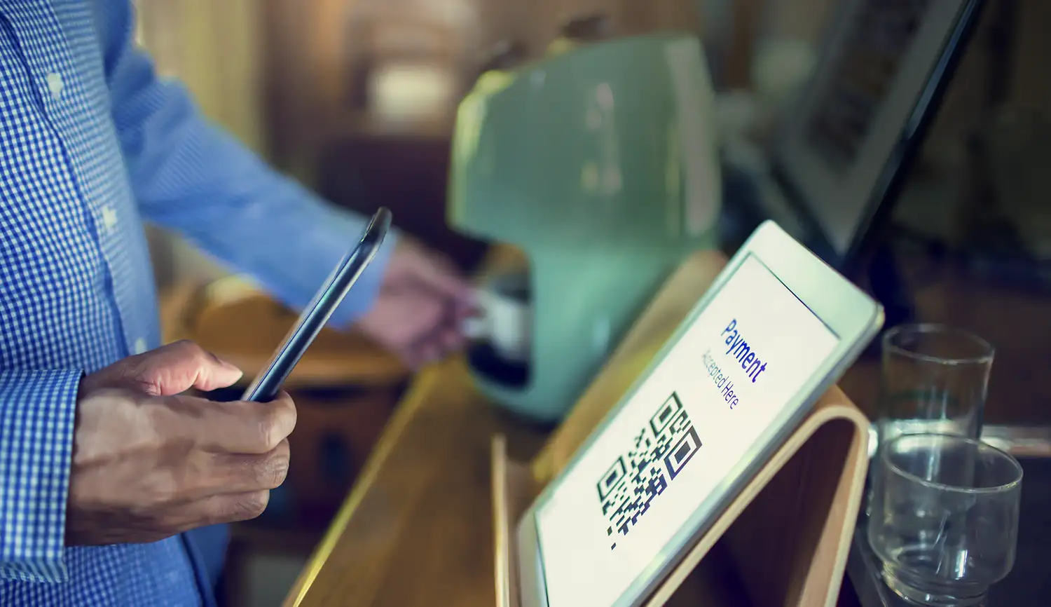 An image of a person using their phone to scan a QR code on a tablet.